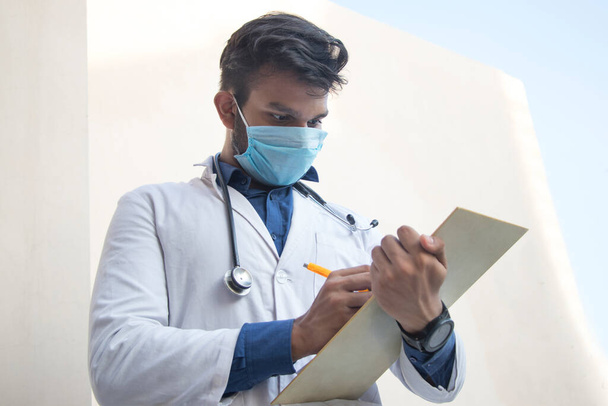 Un operatore sanitario in camice da laboratorio Scrivere un blocco note e una penna - Foto, immagini
