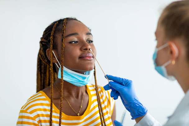 Black woman getting nasal coronavirus swab test at hospital - Fotoğraf, Görsel