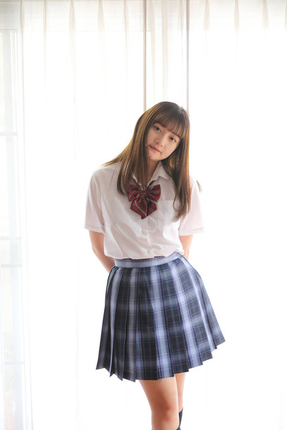 Japon liseli kız üniforması beyaz tonlu yatak odasında. - Fotoğraf, Görsel