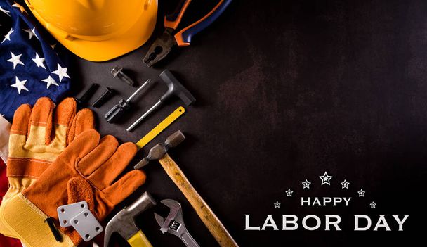 Happy Labor day concept. Amerikaanse vlag met verschillende bouwgereedschappen en de tekst op donkere stenen achtergrond. - Foto, afbeelding