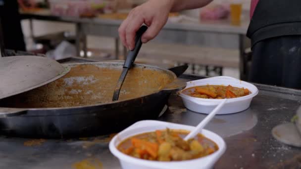 Pouliční kuchař připravuje zeleninové dušené maso na prodej v litinovém kotli. 4K - Záběry, video