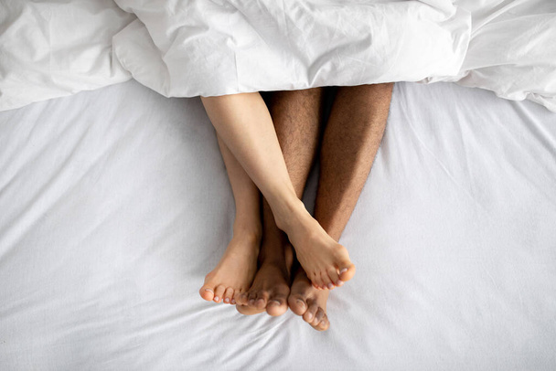 Vista superior de la joven pareja multirracial acostada en la cama después de hacer el amor. Juegos eróticos, juegos sexuales previos, relación íntima - Foto, imagen