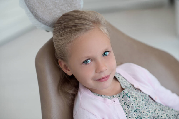 Söpö blondi tyttö istuu tuolissa hammaslääkäreillä - Valokuva, kuva