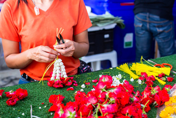 Asian woman staff is stringing flower garlands in flower shop at Bangkok flower market, Thailand. - Photo, Image