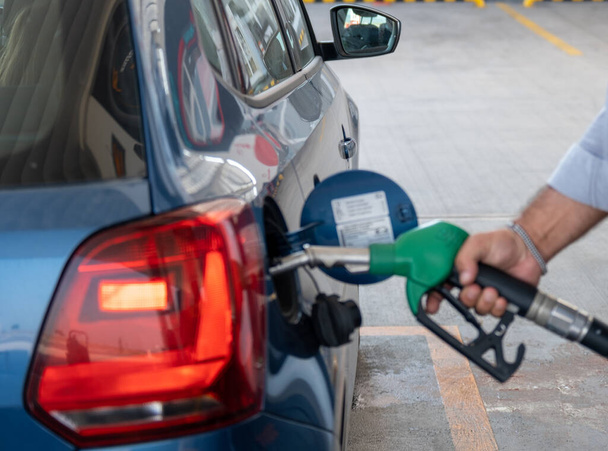 Una mano de un hombre mostró mientras repostaba su coche, bomba de combustible en el tanque de suministro, hombre vertiendo aceite de gasolina en la gasolinera - Foto, imagen