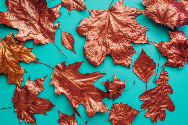 Conjunto de hojas de bronce sobre fondo turquesa. Concepto natural de otoño. Vista superior, plano. - Foto, imagen
