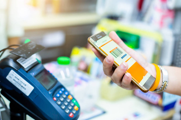 Selektive Fokussierung auf die Kundenhand hält Smartphone zum Bezahlen im Geschäft. Das Konzept des digitalen Zahlungsverkehrs ohne Geld. - Foto, Bild