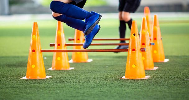 Вибірковий фокус для дитячого футболіста, який біжить і стрибає поперечним конусом і маркером перешкод. Дитячий футбольний тренінг
. - Фото, зображення