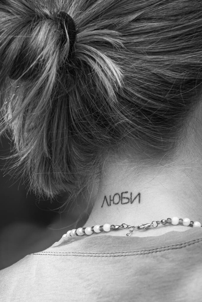 Neck tattoo. A tattooed word. The symbolism of love. Girl with a tattoo. Inscription on the skin. Tattoos about love and feelings. Self-expression of a person. Women's bodypainting. Romantic words. - Photo, Image