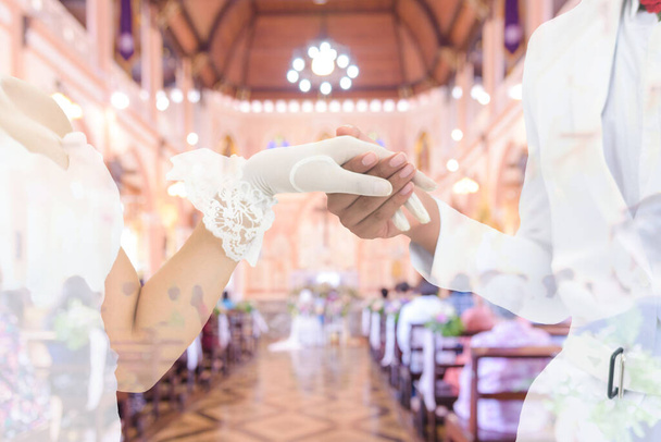 Onderwerp Bruiloft: Dubbele belichting van De bruidegom en de bruid in een witte trouwjurk, elkaars handen vasthoudend.. - Foto, afbeelding