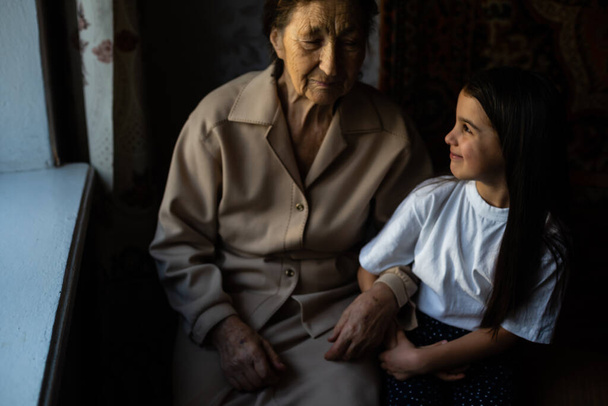 Unrecognizable grandmother and her granddaughter holding hands. - Foto, imagen