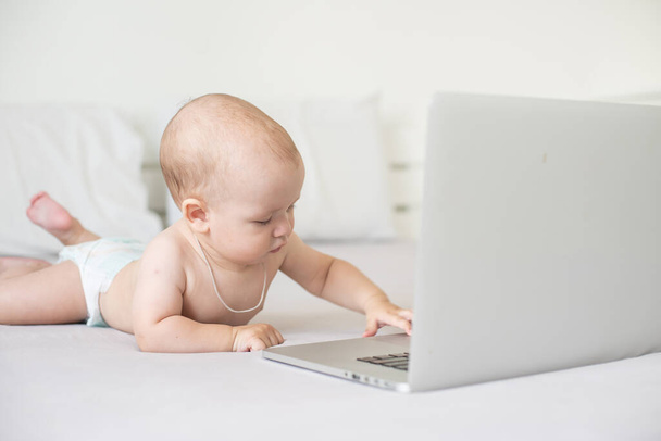 Un bebé y una computadora, un portátil con foto en la cabeza - Foto, imagen