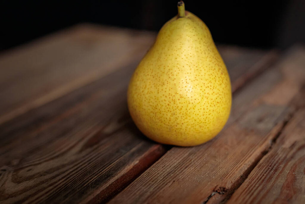 Juicy yellow pear on a wooden background from old boards in a low key. - Foto, immagini