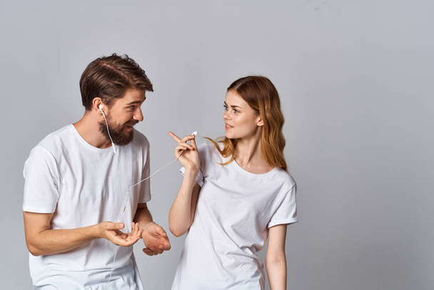giovane coppia in t-shirt bianche indossando cuffie ascoltare musica tecnologia intrattenimento - Foto, immagini