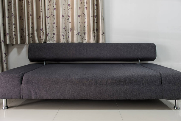 O sofá de tecido preto moderno que é ajustável à cama quando dormir, perto da janela com cortina na casa da cidade, vistas de fonte para o espaço de cópia. - Foto, Imagem