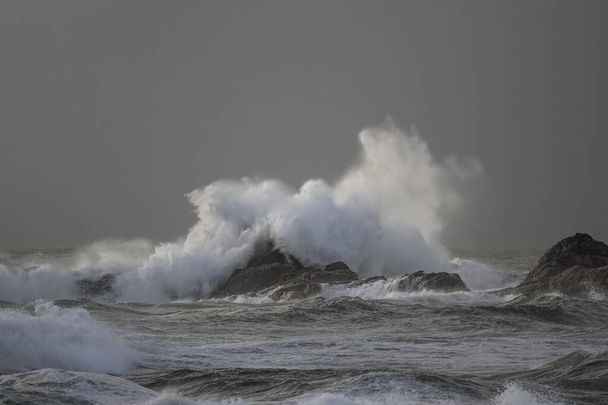 Tempête sur la côte voir une grosse vague se briser sur les rochers et les falaises voir éclabousser et pulvériser au coucher du soleil - Photo, image