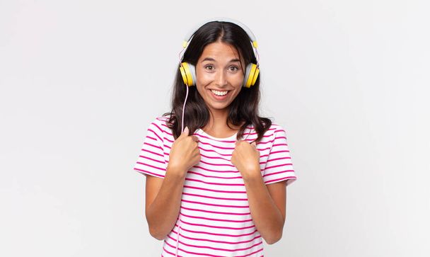 young hispanic woman feeling happy and pointing to self with an excited listening music with headphones - Foto, immagini