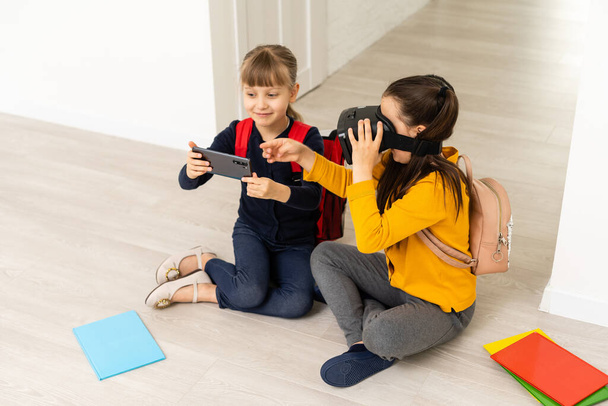 Nieuwe technologieën uitproberen. Klein schoolmeisje draagt grote VR bril wordt onder de indruk het spelen van virtuele games op school. - Foto, afbeelding