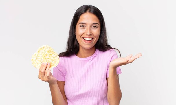 giovane donna ispanica sentirsi felice, sorpreso realizzando una soluzione o un'idea e tenendo un biscotto di riso. concetto di dieta - Foto, immagini