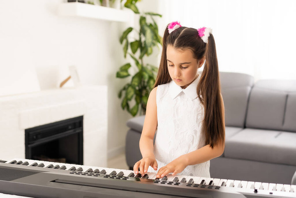 hermosa chica canta mientras toca en un piano electrónico - Foto, imagen