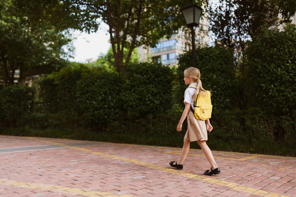 Schoolgirl back to school after summer vacations. Child in uniform smiling early morning outdoor.  - Zdjęcie, obraz