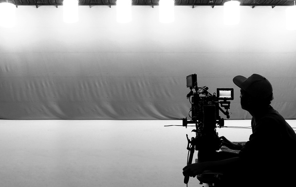 Videogyártás a színfalak mögött. Reklámfilm készítése, a filmes csapat Lightman és operatőr együtt dolgozik a filmrendezővel a stúdióban. filmgyártási koncepció. Sziluett stílus. - Fotó, kép