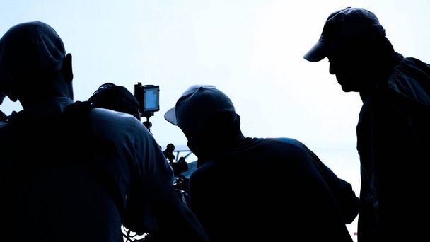 Videoproductie achter de schermen. Het maken van TV commerciële film dat filmcrew team lightman en cameraman samen te werken met filmregisseur in de studio. filmproductieconcept. Silhouet stijl. - Foto, afbeelding