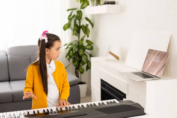 little girl play piano in class education with laptop in home online learning in covid-19 crisis quarantine - Photo, Image