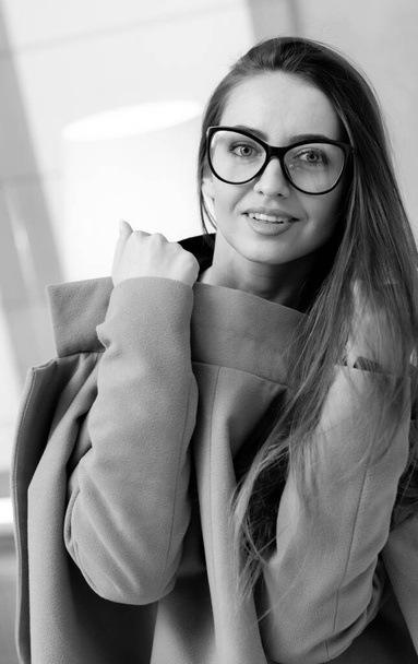 Pretty woman in glasses. Black and white photo of the beautiful female wearing eyewear standing and looking at the camera - Photo, image
