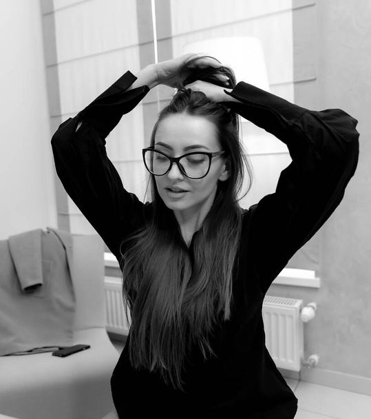 Relaxed calm woman in stylish clothes standing and posing in glasses with eyes closed. Woman touching to her hair - Fotografie, Obrázek