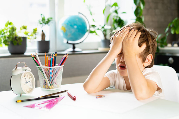 Kisfiú házi feladatot csinál otthon az asztalnál, túlhajszolja az elsősöket a tanulástól, stresszeli őket egy iskolás. - Fotó, kép