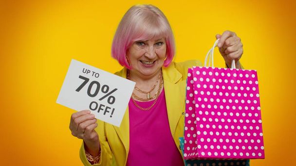 Idős nagymama nő bemutató bevásárló táskák és akár 70 százalékos Off feliratok szöveget, Fekete péntek - Fotó, kép