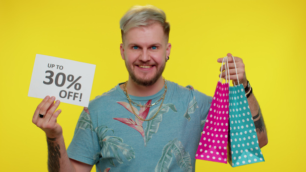 Cheerful tourist man showing shopping bags and Up To 30 Percent Off inscriptions banner Black Friday - Foto, Bild