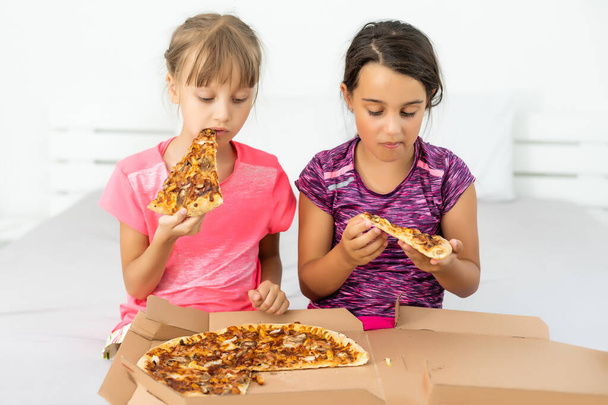 Two pretty young girls eating a slice of pizza - Foto, Imagem