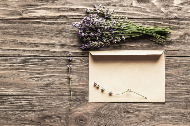 Lavender bouquet and paper envelope on a wooden table. Concept for advertising background, wedding invitations, celebration, with place for text. - Valokuva, kuva