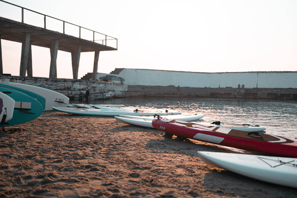 Weitere Sup Boards liegen am Ufer des Sees bei Sonnenuntergang am Wasser - Foto, Bild