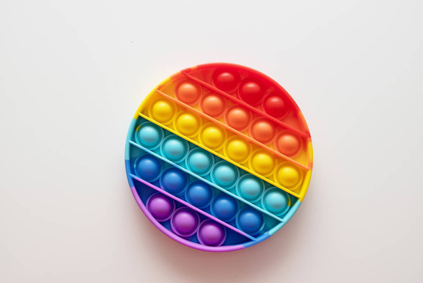 Rainbow pop it juguetes fidget sobre un fondo blanco, cama plana. Espacio para texto - Foto, Imagen