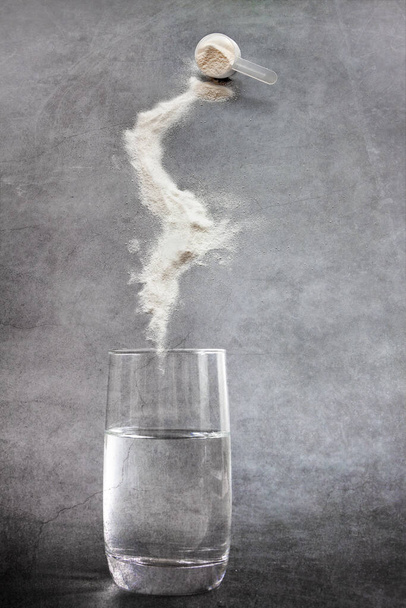 El polvo de colágeno mide la cuchara y el vidrio de agua beben fondo de hormigón oscuro. Sostenibilidad, belleza y concepto de vida saludable - Foto, Imagen