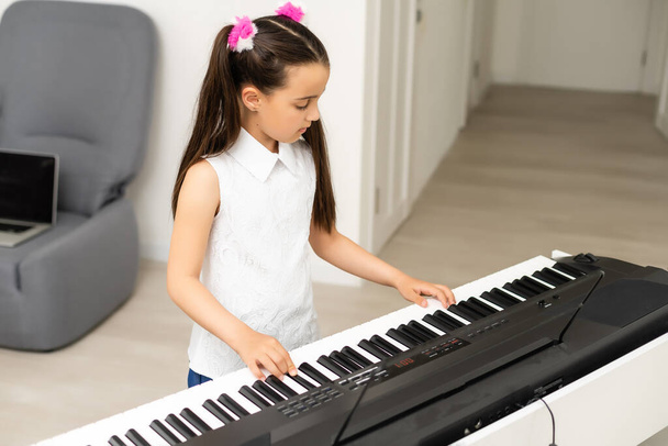 hermosa chica canta mientras toca en un piano electrónico - Foto, imagen