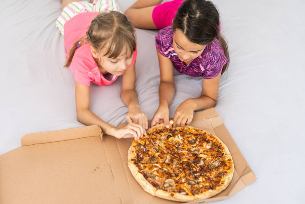 Dwie ładne młode dziewczyny jedzące kawałek pizzy - Zdjęcie, obraz