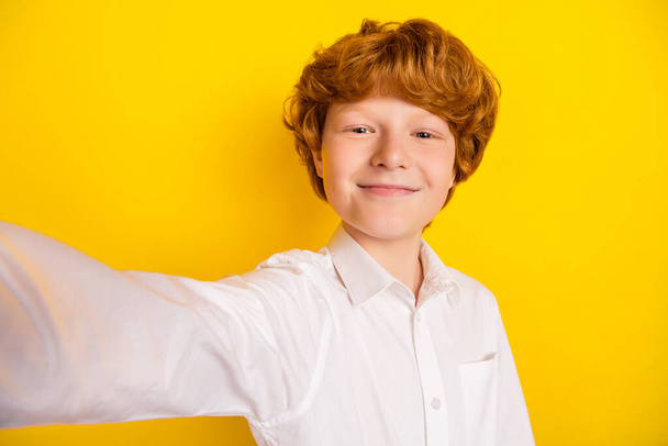 Portrait of young handsome good-looking smiling boy take selfie smart first-grader isolated on yellow color background - 写真・画像