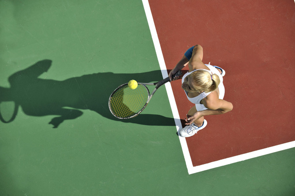 Young fit woman play tennis outdoor on orange tennis field at early morning - Foto, Imagen