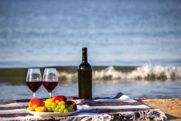 Picnic blanket, wine, fruit, beautiful sea beach Nature Selective focus - Photo, Image