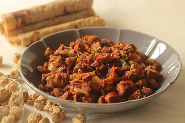 Dry roasted soya chunks with onions tomatoes and spices. Prepared with Kerala style meat masala in coconut oil. Served with indian flatbread. Shot on white background - Photo, Image