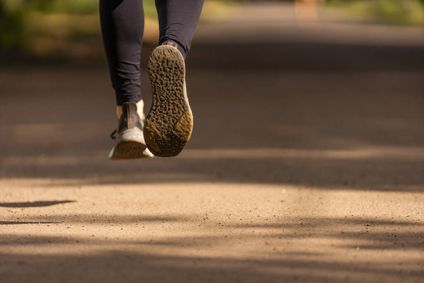 Runner feet running on road closeup on shoe. woman fitness sunrise jog workout welness concept. - Photo, Image