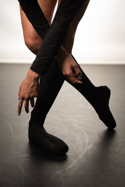 Pernas de bailarina jovem com sapatos pontiagudos dançando em um fundo de chão preto. Treino de ballet. Pés de bailarina de ballet. - Foto, Imagem