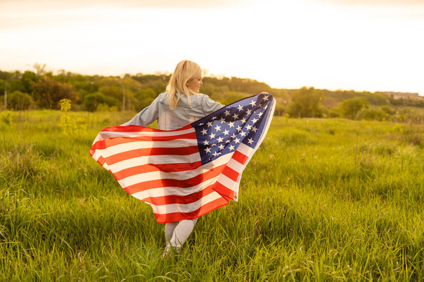 kraj, patriotyzm, Dzień Niepodległości i koncepcja ludzi - szczęśliwa uśmiechnięta młoda kobieta z narodową flagą amerykańską na polu - Zdjęcie, obraz