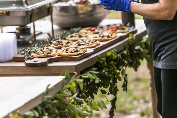 屋外の夏のパーティーイベントでケアラーによって作られた木製のまな板の上に手作りの個人的なピザ - 写真・画像