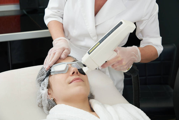 Young woman receiving laser treatment in cosmetology clinic - Foto, afbeelding