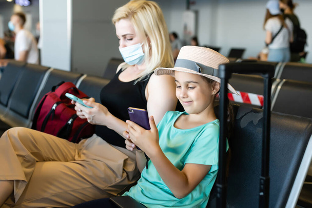 feliz jovem mãe com a filha no aeroporto, enquanto espera por seu voo - Foto, Imagem